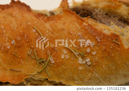 Delicious crusty bread topped with sea salt and herbs, showcasing the art of baking in a rustic kitchen setting Delicious crusty bread topped with sea salt and herbs, showcasing the art of baking in a rustic kitchen setting 135181236
