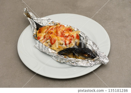 Deliciously baked fish wrapped in foil with vibrant toppings creates a culinary delight ready for serving Deliciously baked fish wrapped in foil with vibrant toppings creates a culinary delight ready for serving 135181286