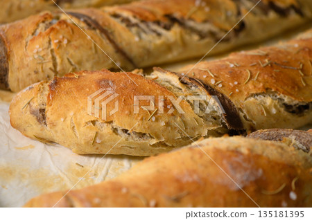 Deliciously baked artisanal bread loaves resting on parchment paper in a cozy kitchen setting Deliciously baked artisanal bread loaves resting on parchment paper in a cozy kitchen setting 135181395