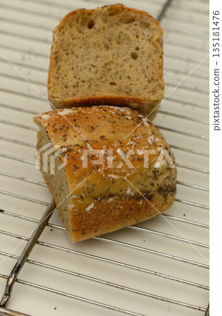 Perfectly baked artisan bread resting on a cooling rack with a beautiful crust and soft interior Perfectly baked artisan bread resting on a cooling rack with a beautiful crust and soft interior 135181476