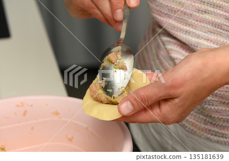 Crafting flavorful dumplings with skillful hands in a cozy kitchen setting Crafting flavorful dumplings with skillful hands in a cozy kitchen setting 135181639