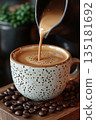 Pouring Milk into a Spotted Patterned Cup Against a Backdrop of Coffee Beans 135181692