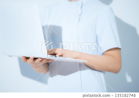 Nurse recruitment with a computer on a light blue background, no face Nurse recruitment with a computer on a light blue background, no face 135182748