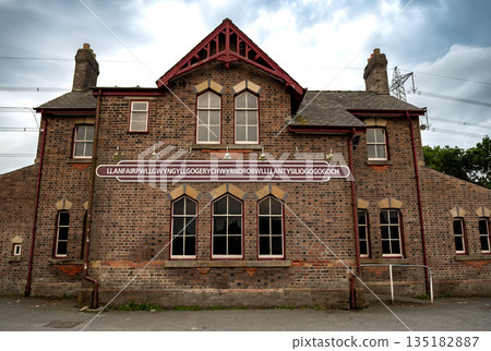 Name Plate On Trainstation Building Of Villag Llanfairpwllgwyngyllgogerychwyrndrobwllllantysiliogogogoch in Wales, UK 135182887