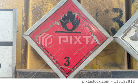 Weathered flammable liquid hazard sign on an industrial container. Weathered flammable liquid hazard sign on an industrial container. 135182918