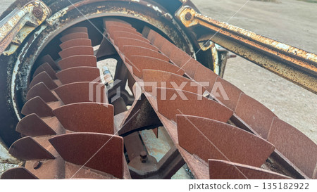 Large industrial rusted metal rotor with blades inside a weathered cylindrical housing. 135182922