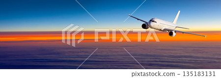 Airplane flying over clouds during a colorful sunset 135183131