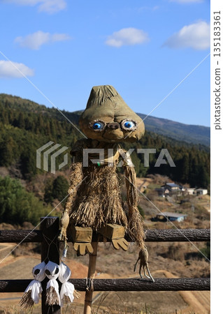 An alien scarecrow made of straw at Sakaori Rice Terraces in Ena City, Gifu Prefecture. Winter-barren rice terraces and mountain village scenery. Early December. An alien scarecrow made of straw at Sakaori Rice Terraces in Ena City, Gifu Prefecture. Winter-barren rice terraces and mountain village scenery. Early December. 135183361