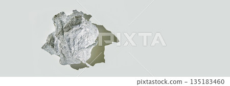 Crumpled aluminum foil ball casting shadow on light gray surface Crumpled aluminum foil ball casting shadow on light gray surface 135183460