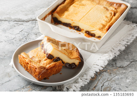 Far Breton is a beloved pudding from Brittany, made of boozy prunes set in a rich custard closeup on the plate. Horizontal 135183693
