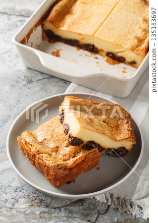 Far Breton is a classic French dessert, a rich, dense custard with dried fruit and rum closeup on the plate. Vertical 135183697