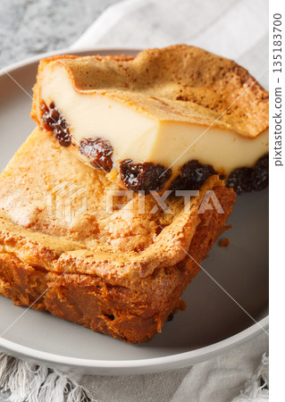 Far Breton is a delicious French dessert baked, creating a thick custardy texture that is enhanced with the flavor of dried prunes and rum closeup on the plate. Vertical 135183700