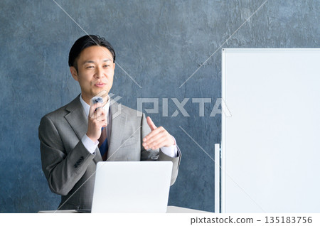 一名男子在白板前演講,他戴著領夾式麥克風。 一名男子在白板前演講,他戴著領夾式麥克風。 135183756