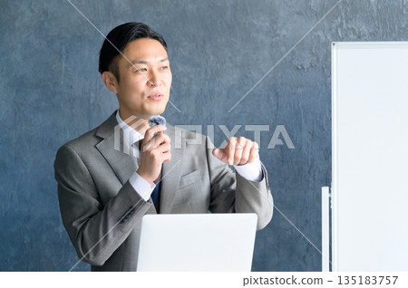 一名男子在白板前演講,他戴著領夾式麥克風。 一名男子在白板前演講,他戴著領夾式麥克風。 135183757