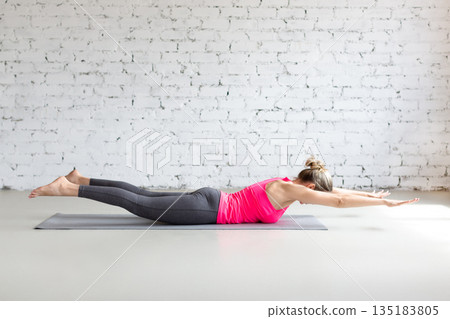 Fit Caucasian woman practice Vipareeta Naukasana exercise indoor in loft studio. Inverted boat pose, yoga. 135183805