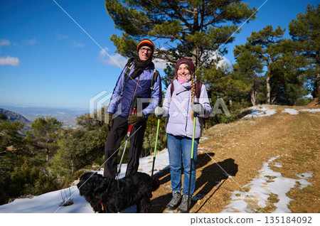 Happy Hikers With Dog On Mountain Trail In Snow Under Bright Blue Sky 135184092