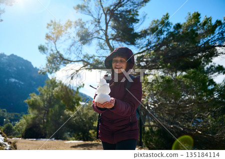 Cheerful Woman Outdoors Holding Snowman On Mountain Trail In Winter Sunshine Cheerful Woman Outdoors Holding Snowman On Mountain Trail In Winter Sunshine 135184114