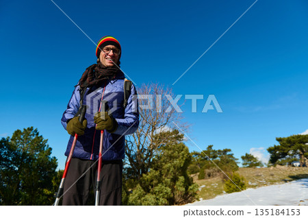 Smiling Man With Trekking Poles Outdoors In Bright Winter Sun Amid Blue Sky Smiling Man With Trekking Poles Outdoors In Bright Winter Sun Amid Blue Sky 135184153