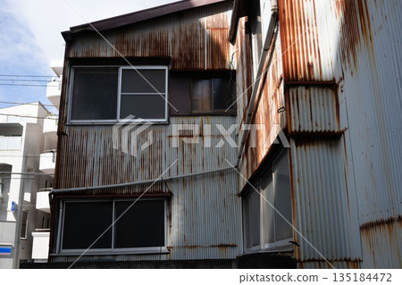 A dilapidated and rusty factory, an abandoned local factory 135184472