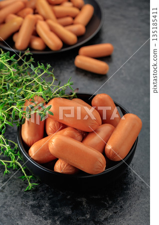 Boiled sausages with thyme on a black stone table. Boiled sausages with thyme on a black stone table. 135185411