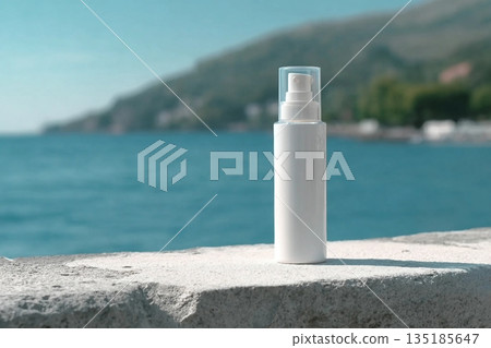 A white bottle with a cream dispenser stands on a white surface, with the sea and mountains in the background. Clean template for brand presentation. 135185647