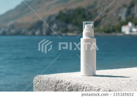 A white bottle with a cream dispenser stands on a white surface, with the sea and mountains in the background. Clean template for brand presentation. 135185652