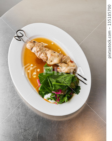 Cooked chicken complemented by bright leafy vegetables and roots 135185700