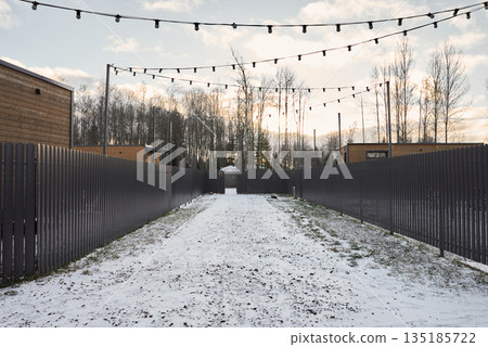 Bright winter passage bordered by fences with overhead illumination 135185722