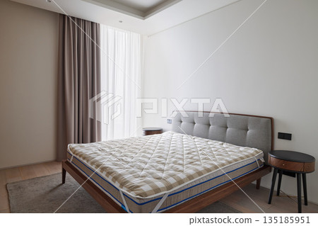 Tranquil bedroom with upholstered headboard and bare mattress 135185951