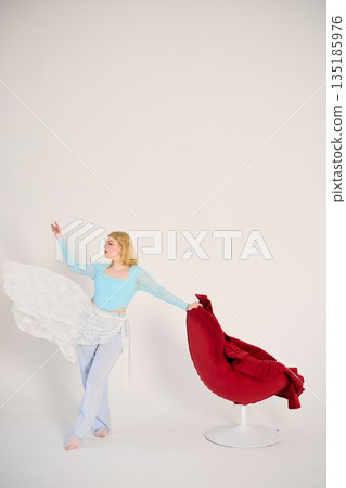 Caucasian lady posing with vibrant chair and flowing apparel 135185976