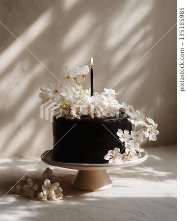 Chocolate cake decorated with flowers and a candle for a special occasion 135185985