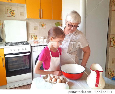 A grandmother and her granddaughter set out the necessary ingredients for cooking. 135186224