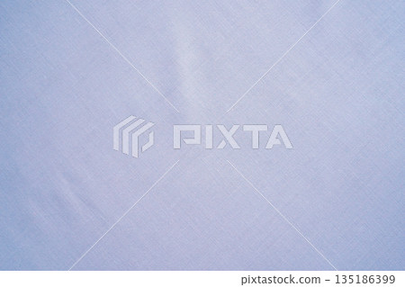 White cotton fabric with a slight blue tint in the shadows. A simple textile with a close-up view of the weave. A plain canvas background with copy space. White cotton fabric with a slight blue tint in the shadows. A simple textile with a close-up view of the weave. A plain canvas background with copy space. 135186399