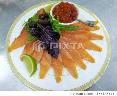 assorted fish: salmon, red caviar, olives and lemon on a large plate 135186444