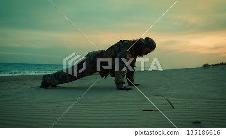 American Navy soldier does push-ups on the beach at sunset for sports training 135186616