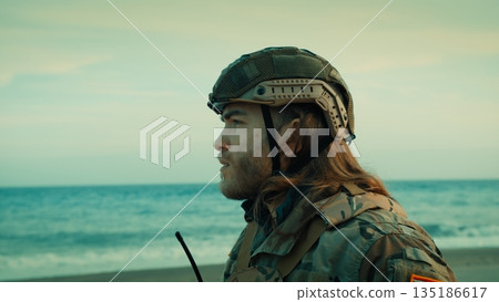 Charming American soldier with long hair wears protective helmet Charming American soldier with long hair wears protective helmet 135186617