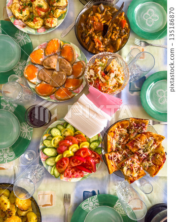 Colorful spread of assorted dishes on table with vibrant plates and glasses Colorful spread of assorted dishes on table with vibrant plates and glasses 135186870