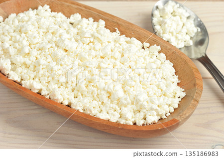 crumbly cottage cheese in a wooden plate 135186983