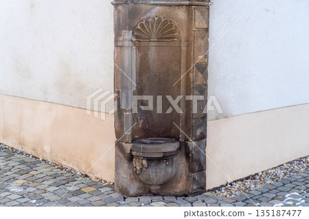 Close-up of an architectural detail: the corner of a light-colored building showing signs of wear, water streaks, and a rusty or soiled drainage element. The wall surfaces demonstrate erosion and wate Close-up of an architectural detail: the corner of a light-colored building showing signs of wear, water streaks, and a rusty or soiled drainage element. The wall surfaces demonstrate erosion and wate 135187477