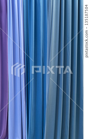 Vertical folds of fabric in various shades of blue 135187584