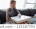 young woman warms up with hot tea in winter weather at home 135187703