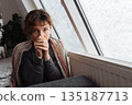 young woman warms herself near radiator at home in winter weather. 135187713