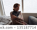 young woman warms herself near radiator at home in winter weather. 135187714
