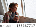 young woman warms up with hot tea in winter weather at home 135187717