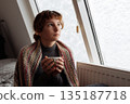 young woman warms up with hot tea in winter weather at home 135187718