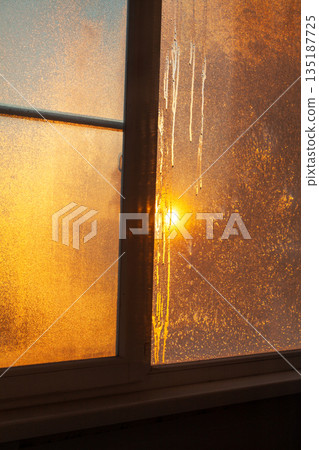 Golden sun shining through frozen window 135187725