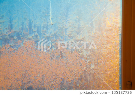 Golden sun shining through frozen window 135187726