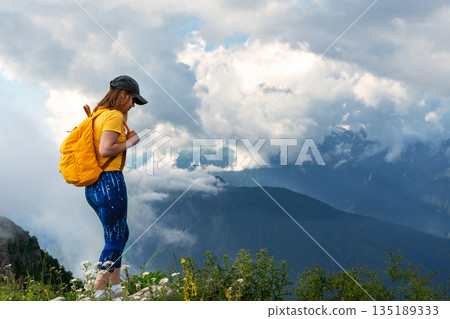 Woman standing on rocky mountain slope,enjoying panoramic views of cloudy mountain landscape, outdoor active lifestyle, and travel inspiration, for hiking, trekking, and eco tourism themes copy space Woman standing on rocky mountain slope,enjoying panoramic views of cloudy mountain landscape, outdoor active lifestyle, and travel inspiration, for hiking, trekking, and eco tourism themes copy space 135189333