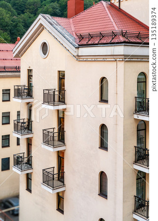 Modern residential building with beige facade , multiple balconies and red roof, Urban architecture with clean lines and neutral colors, suitable for real estate and city living concepts Modern residential building with beige facade , multiple balconies and red roof, Urban architecture with clean lines and neutral colors, suitable for real estate and city living concepts 135189374