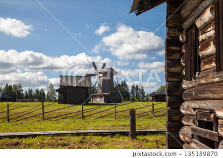 Old Wooden Village with Log Houses, Barns, and Windmill 135189870